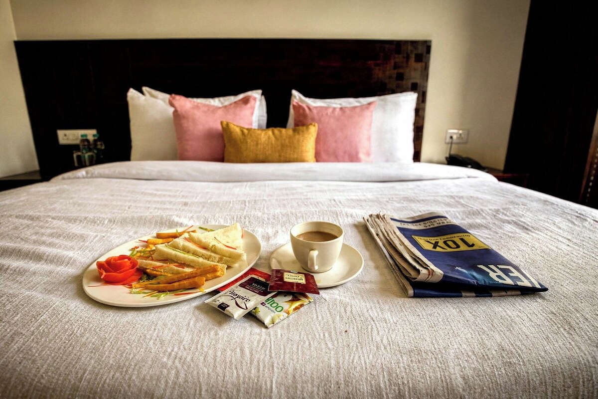 Un letto rifatto con cura, un vassoio per la colazione, una tazza di caffè e un giornale.