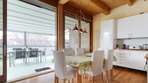 Eine moderne Küche mit weißen Schränken, einer Holzbalkendecke und einem Essbereich mit Tisch und Stühlen.