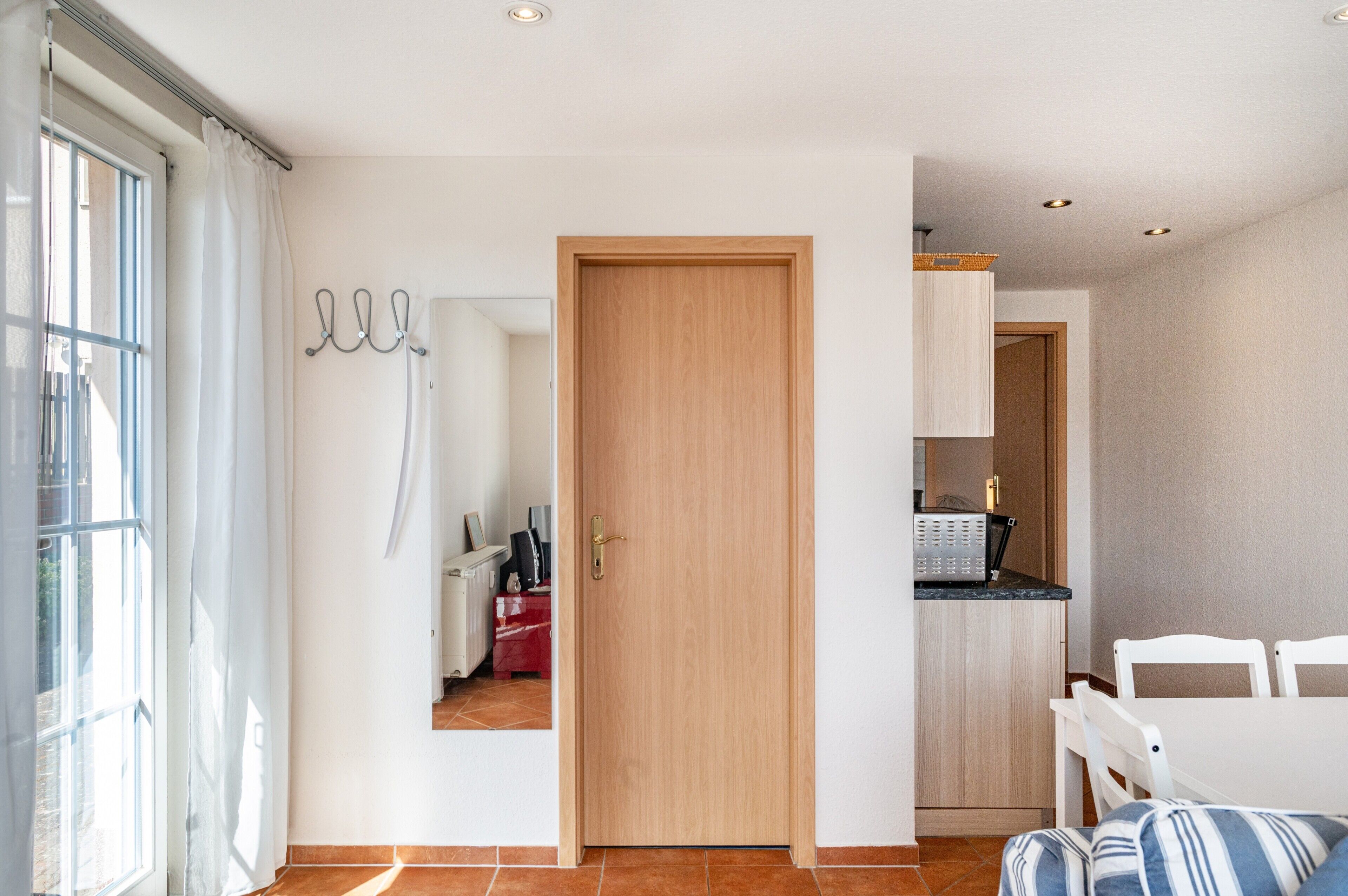 A room with a wooden door, a white table, and a window with curtains.