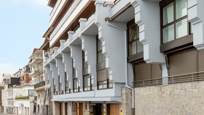 A modern multi-story building with balconies, a stone facade, and a clear sky. - Maskortxo - Basque Stay (San Sebastián)