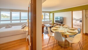 A modern hotel room with a large bed, a dining area with a table set for four, and a television. - Maskortxo - Basque Stay (San Sebastián)