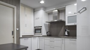 A modern kitchen with white cabinetry, a built-in oven, and a stainless steel range hood. - Ordulari - Basque Stay (San Sebastián)