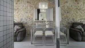 A room with a stone wall, a large mirror, a dining table with chairs, and two sofas. - Ordulari - Basque Stay (San Sebastián)