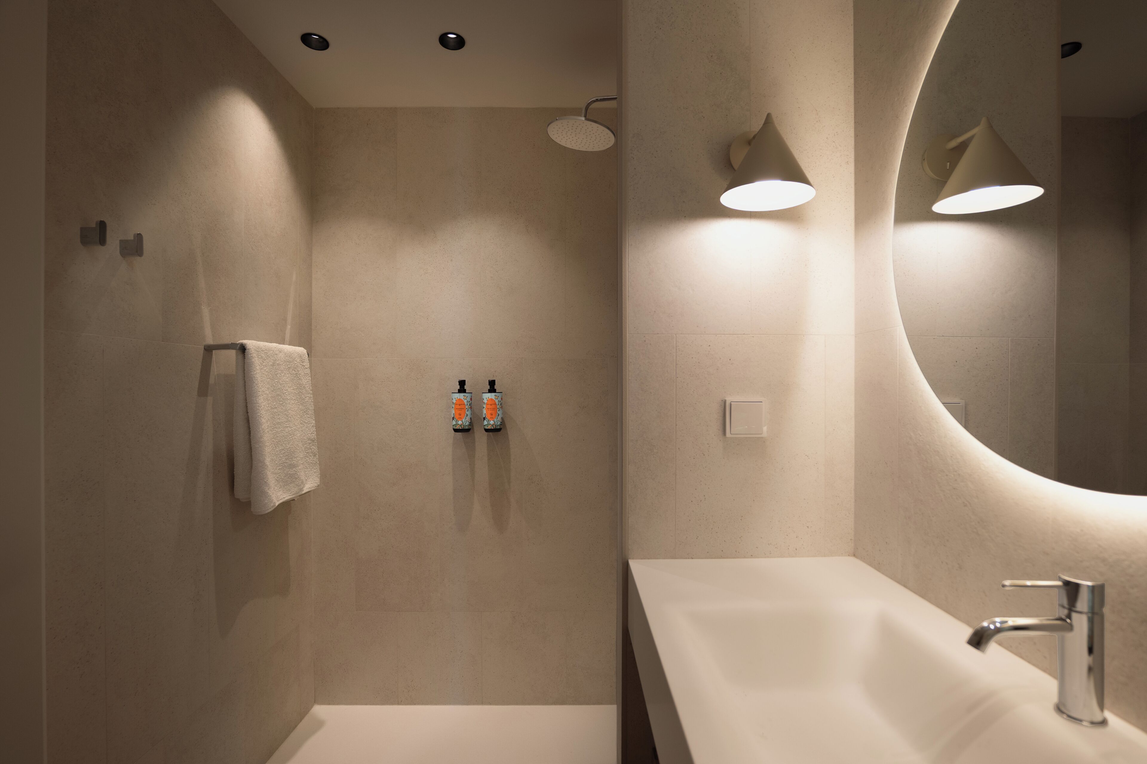 Un baño moderno con un espejo grande, un lavamanos y dos dispensadores de jabón en la pared.