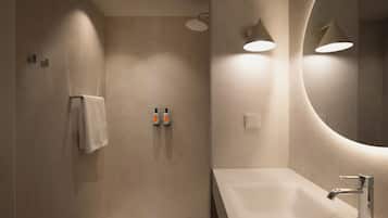 Un baño moderno con un espejo grande, un lavamanos y dos dispensadores de jabón en la pared.