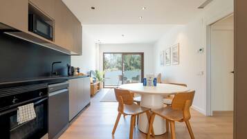 Una cocina moderna con microondas, estufa y comedor con sillas y una mesa.