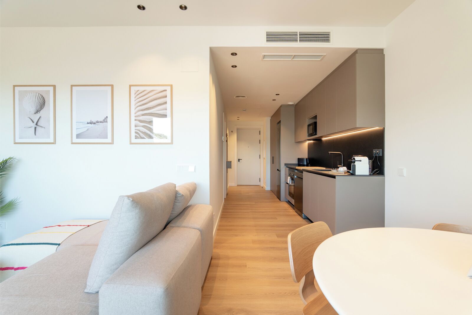 A modern living room with a sofa, a dining table, and a kitchen area with a microwave.