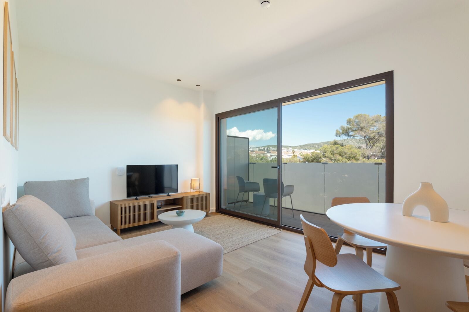 A modern living room with a sofa, TV, and dining area.