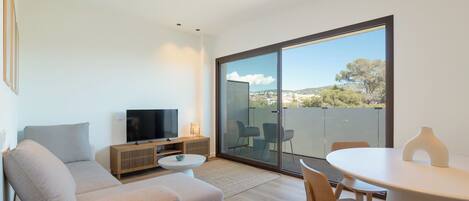 A modern living room with a sofa, TV, and dining area.