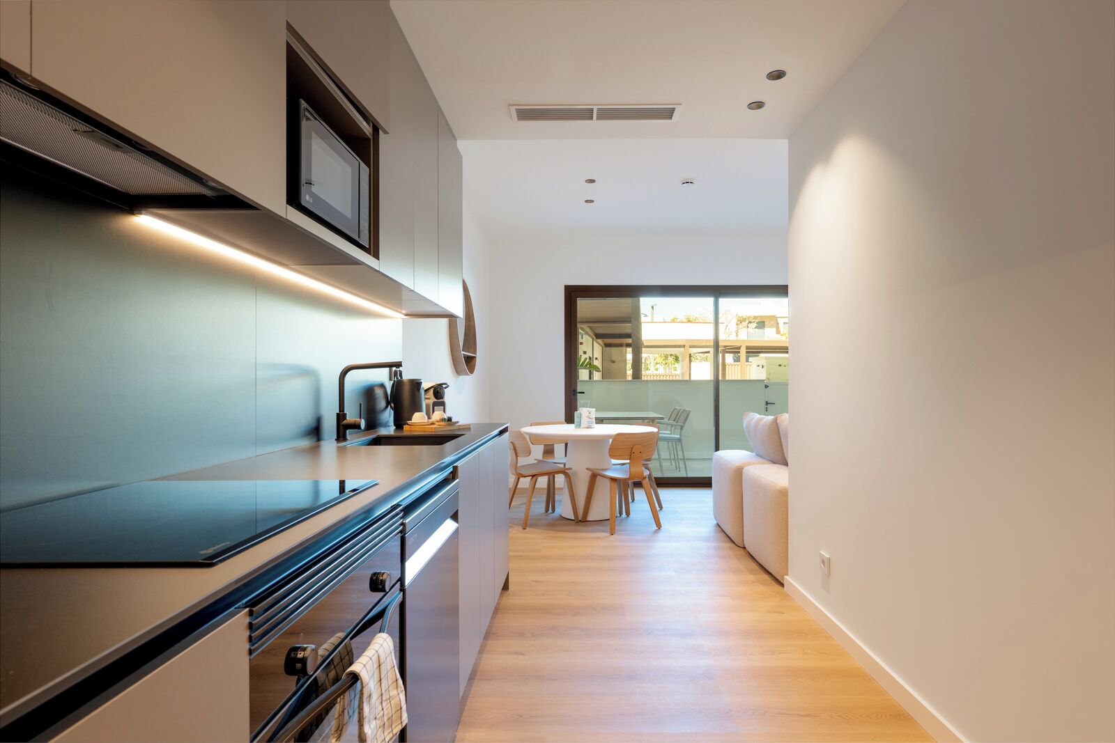 Una cocina moderna con microondas integrado, cafetera y comedor con mesa y sillas.