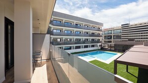 Ein modernes Gebäude mit mehreren Balkonen, einem Schwimmbad und Blick zum Himmel.