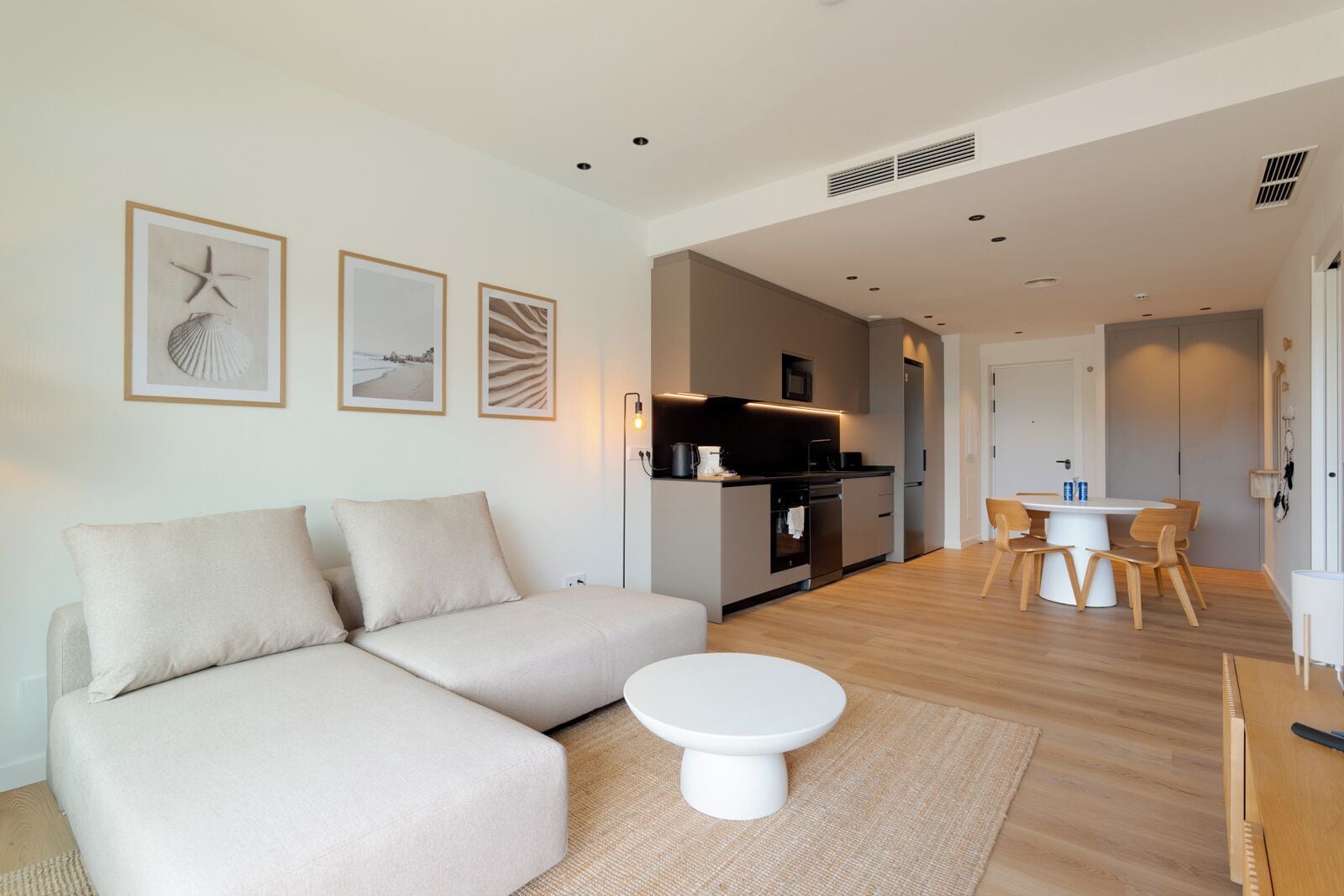 A modern living room with a sofa, a coffee table, and a dining area with a table and chairs.