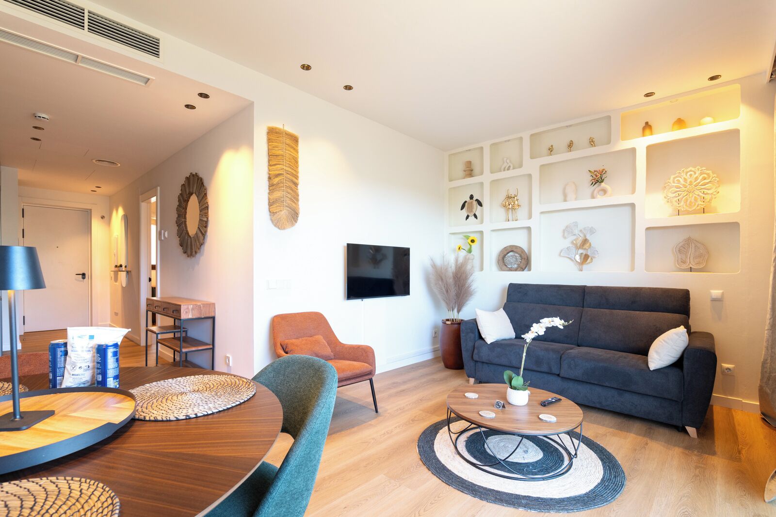 Ein modernes Wohnzimmer mit einer Couch, einem Couchtisch und einem an der Wand befestigten Fernseher.