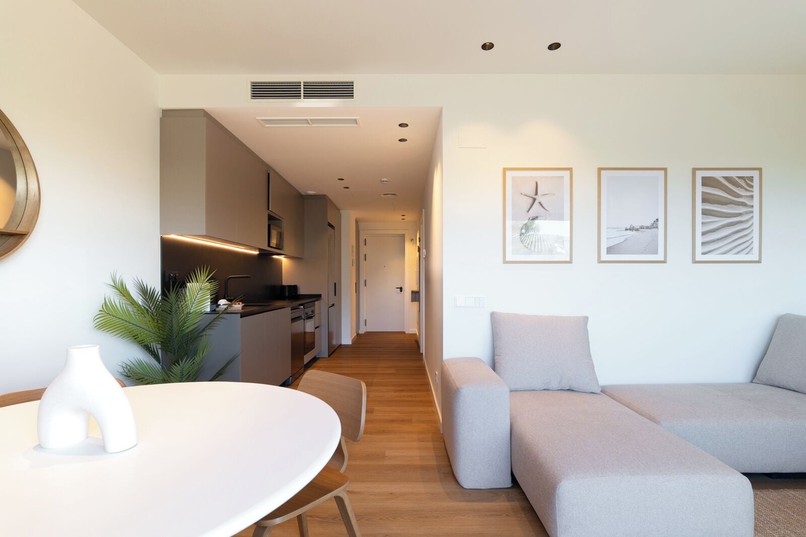 Una sala de estar moderna con un sofá, una mesa de comedor y una cocina al fondo.