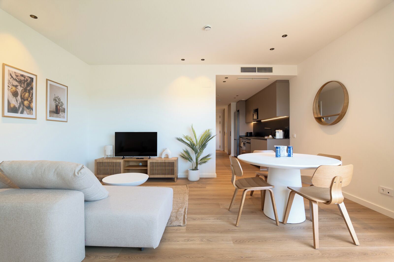 Ein modernes Wohnzimmer mit Sofa, Fernseher, Esstisch und Stühlen.