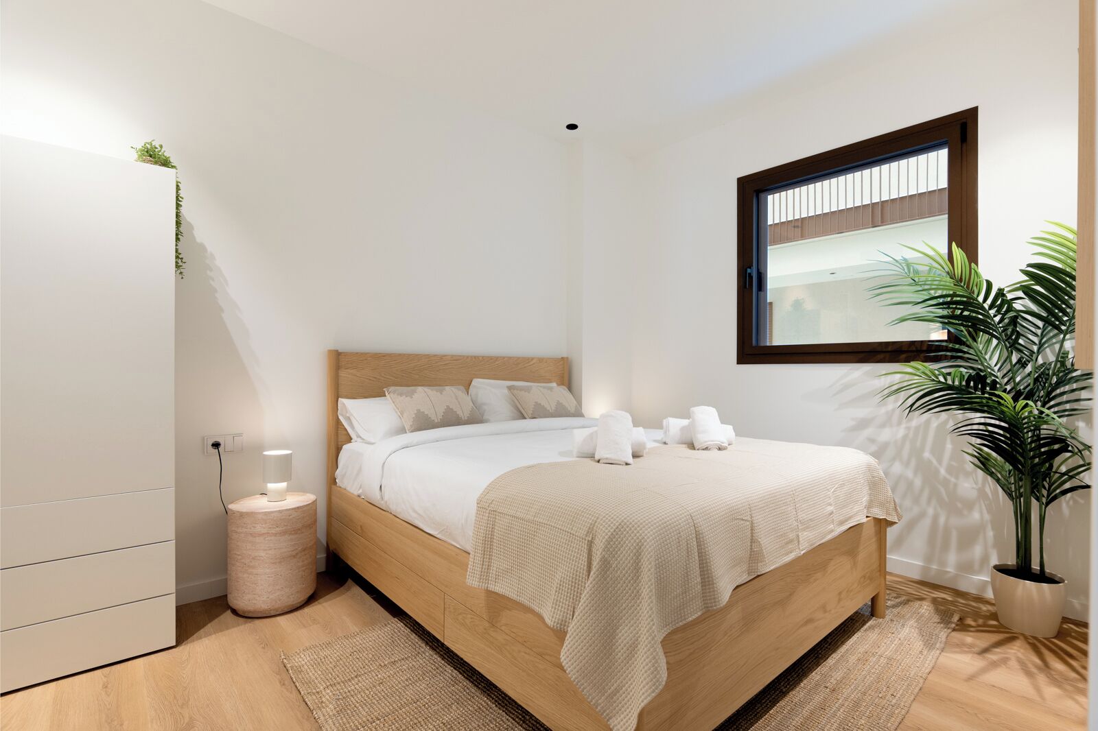 Quarto moderno com cama de madeira, abajures, uma planta em vaso e janela.