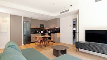 A modern living room with a sofa, a TV, and a dining area with a table and chairs.