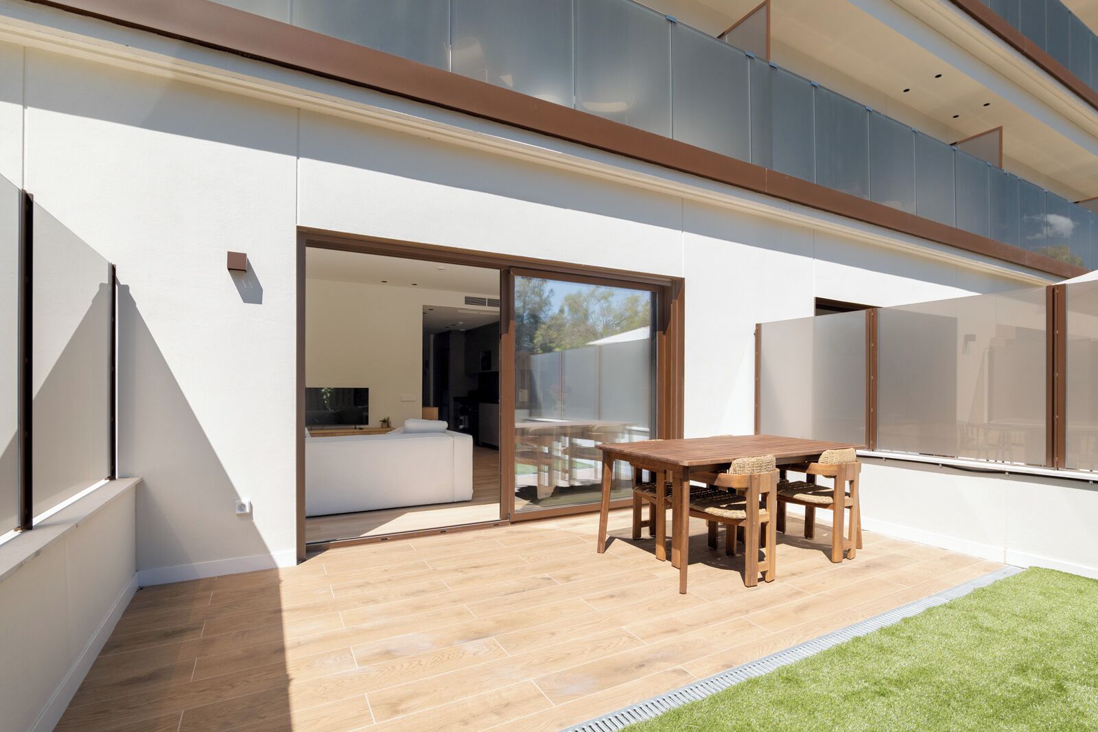 A modern house with a patio, a dining table, and a sofa.