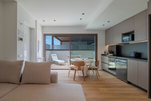 Une cuisine moderne avec un coin repas, un canapé et une vue sur l’extérieur grâce à une porte vitrée.