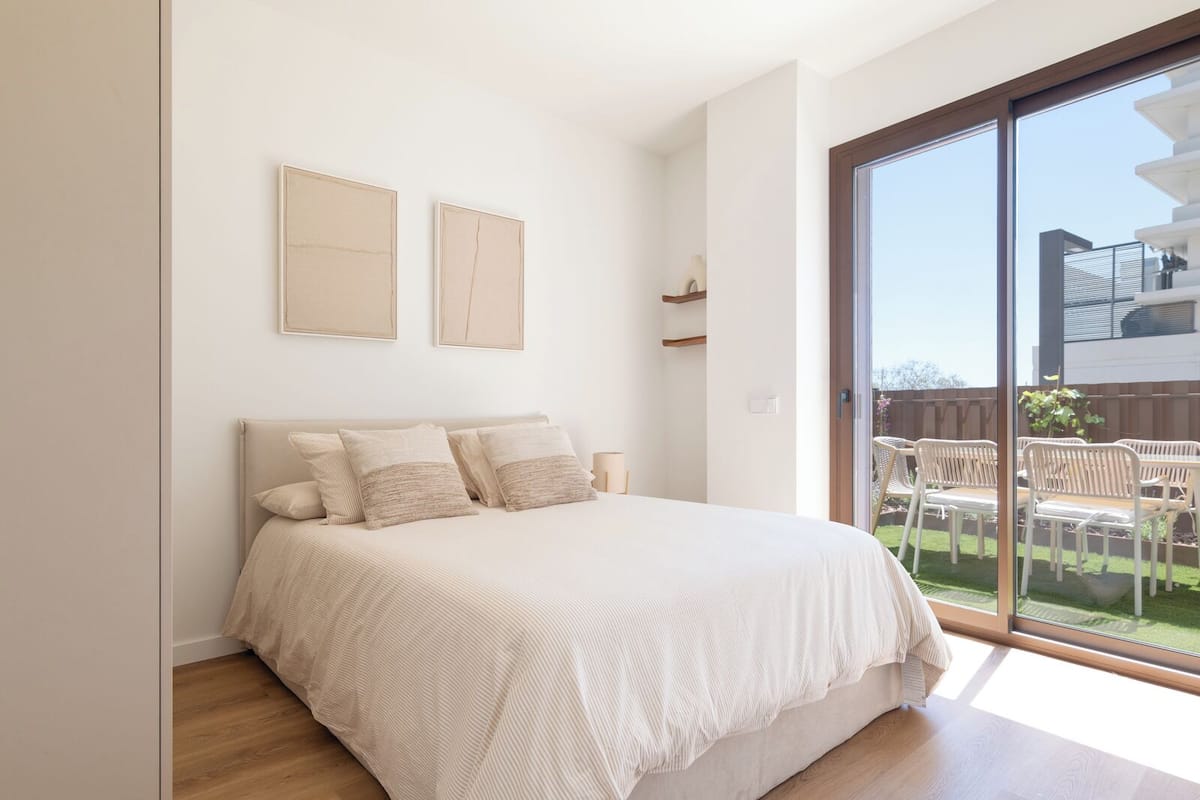 Un dormitorio con cama, un ventanal y vistas al exterior.