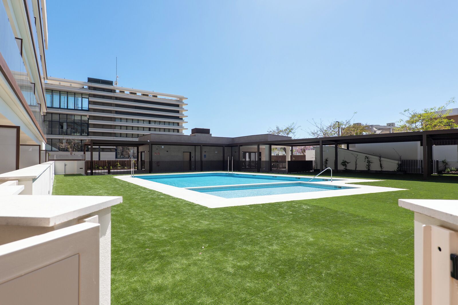 Un edificio moderno con piscina circondata da erba sintetica.