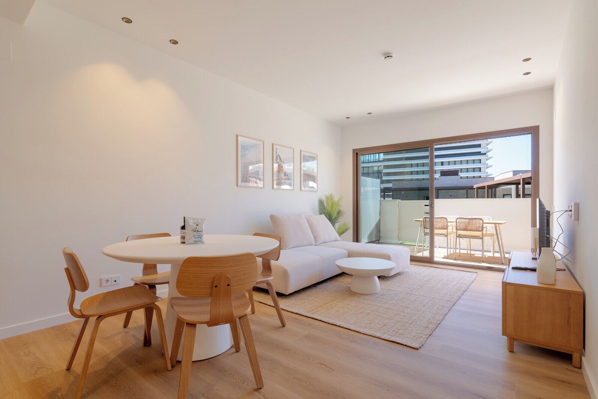 A modern living room with a round dining table, a sofa, and a small coffee table.
