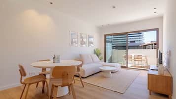 A modern living room with a round dining table, a sofa, and a small coffee table.
