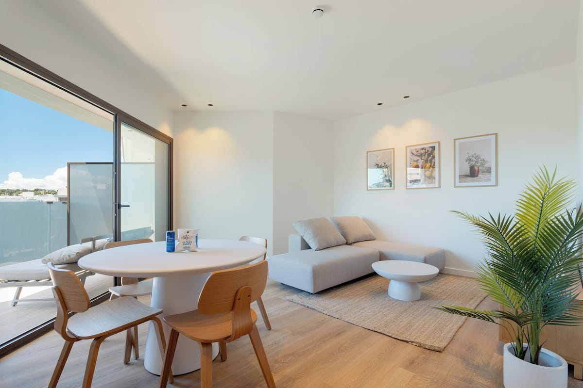 Una sala de estar moderna con una mesa redonda, dos sofás y una planta en maceta.