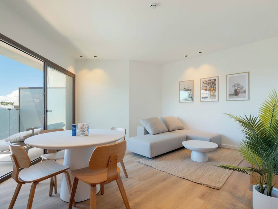 A modern living room with a round table, two sofas, and a potted plant.