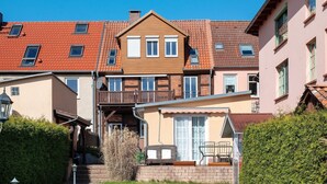 A residential building with a balcony, a small porch with a chair, and a pathway leading to the entrance. - Apartment 'Fewo Schwan' with Wi-Fi (Malchow)