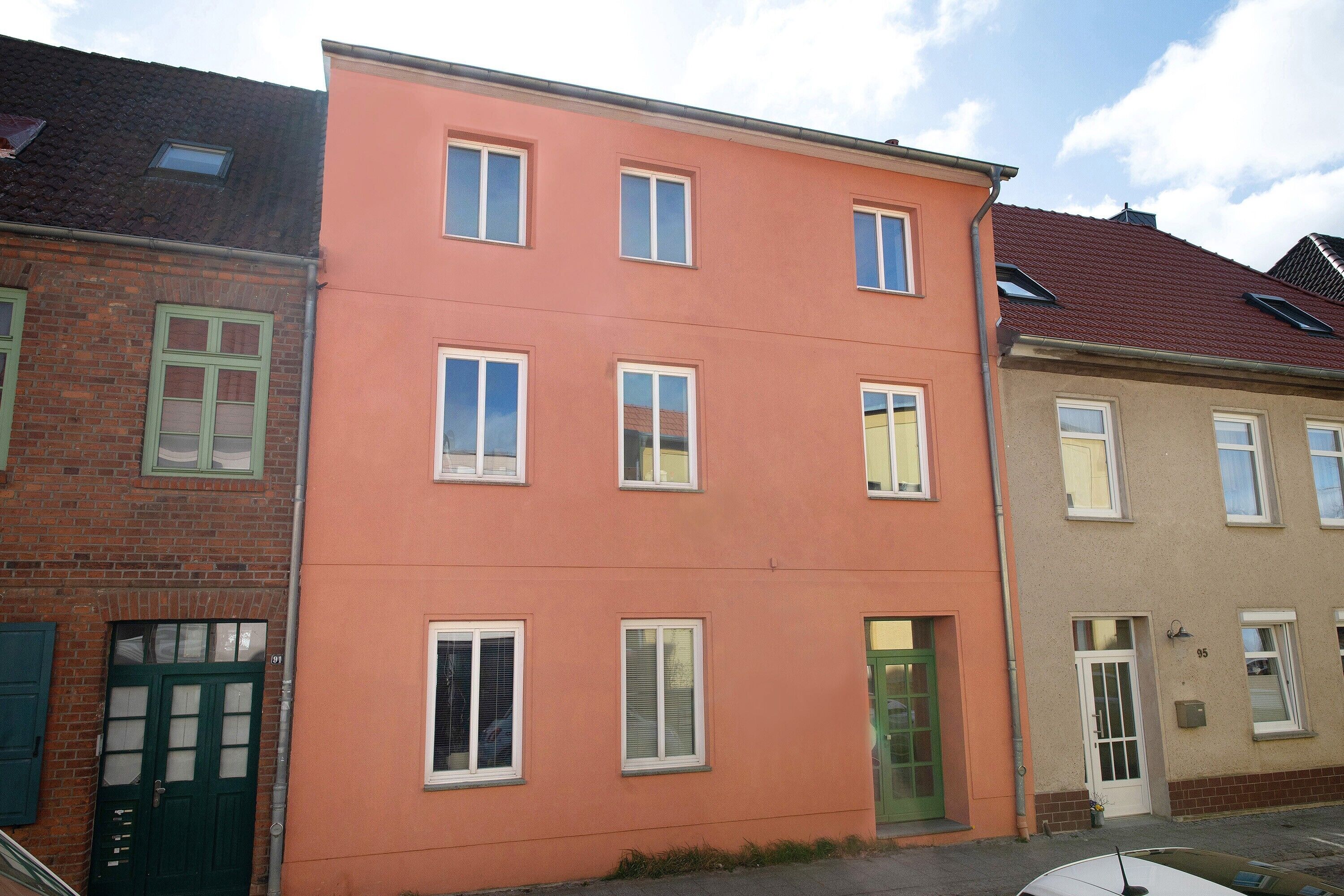 Ein mehrgeschossiges Gebäude mit einer flachen Fassade, zahlreichen Fenstern und einer Tür.