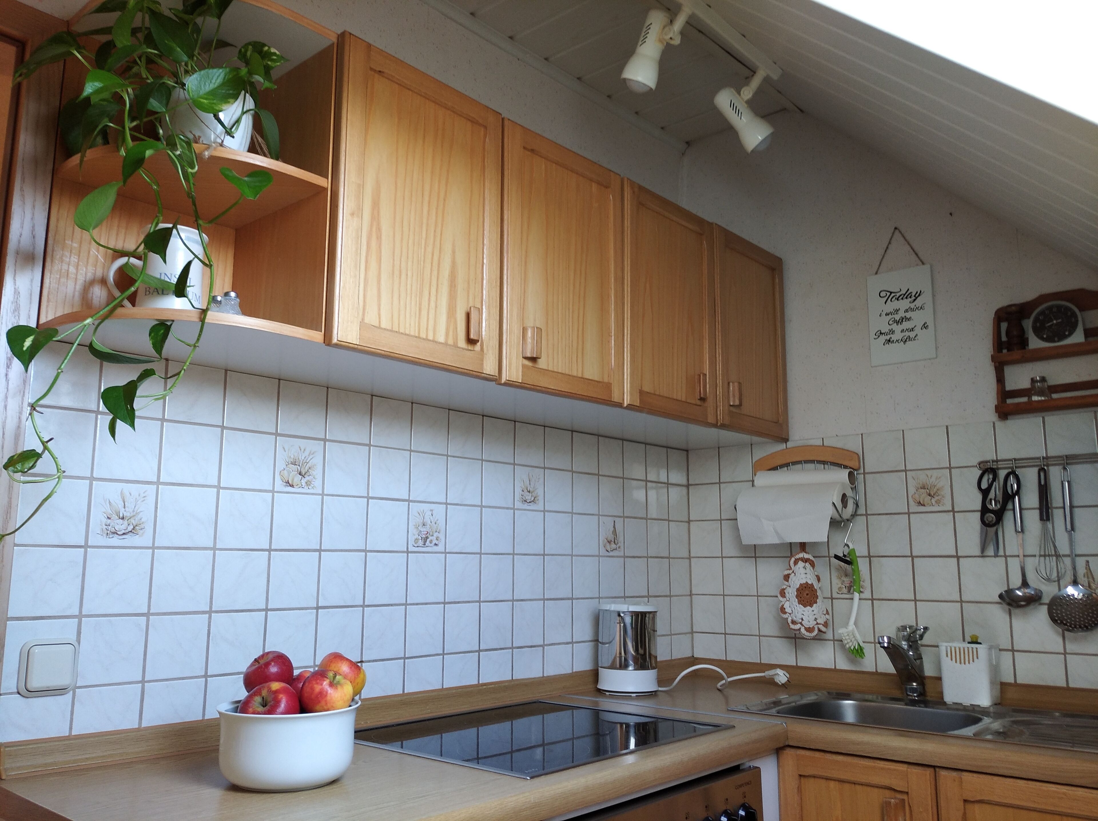 Eine Küche mit Holzausstattung, einer gefliesten Spritzschutzleiste, einem Spülbecken und einer Schüssel Äpfel.