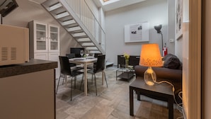 En modern lägenhet med ett matområde, en soffa, en lampa och en trappa.
