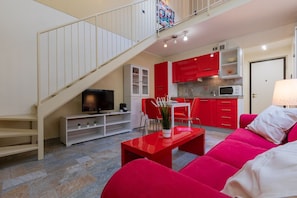 A modern living room with a red sofa, a TV, and a staircase leading to an upper level. - Loft Vermouth by Wonderful Italy (Torino)