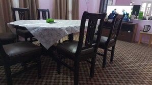 A dining area with a table covered by a floral tablecloth, surrounded by wooden chairs. - Annapurna Himdrishya Pokhara Homestay (Pokhara)