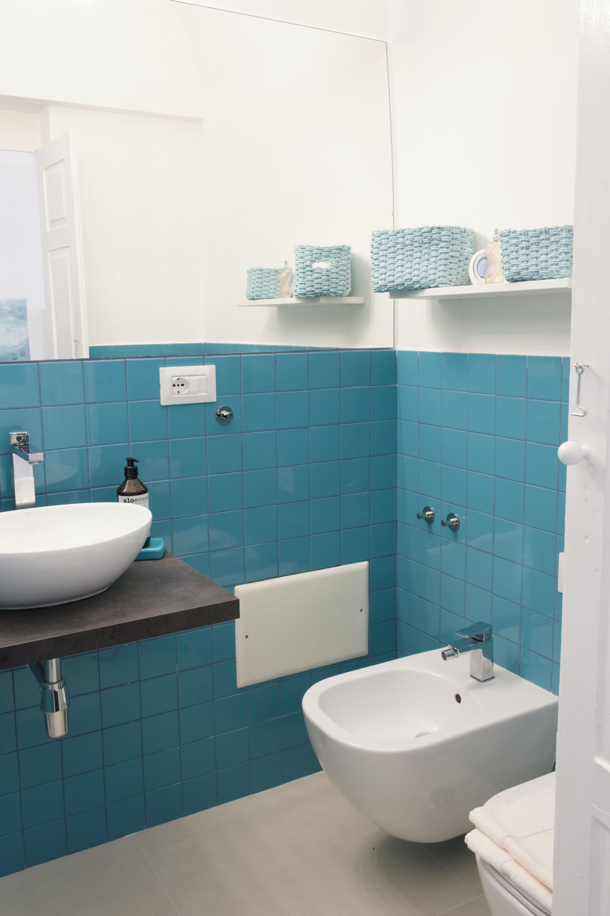Une salle de bain avec un lavabo blanc, un bidet et des murs recouverts de carreaux bleus.