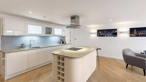 Una cucina moderna con mobili bianchi, un'isola centrale e vista sulla città.