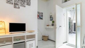Moderni huone, jossa on taulutelevisio, kori ja ovi, joka johtaa ulkotilaan.