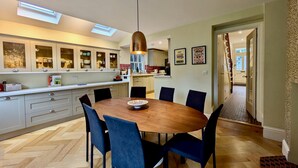 Une cuisine moderne avec un coin repas, comprenant une table en bois, des chaises bleues et un luminaire suspendu.