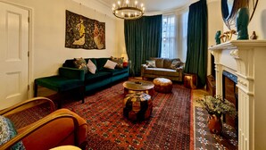 Un salon traditionnel avec un canapé vert, un tapis à motifs et une cheminée.