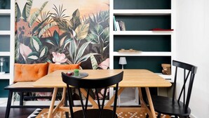 A dining area with a wooden table, black chairs, a cushioned bench, and a bookshelf with books and decorative items. - Chic One-bedroom Apartment in London (London)