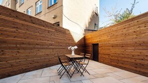 A courtyard with a wooden fence, a table with chairs, and a vase. - Stylish Ground-floor Retreat in Notting Hill (London)