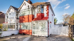 A two-story house with a red brick facade, large windows, and a white picket fence. - Modern Apartment in Enfield With Comfort (Enfield)