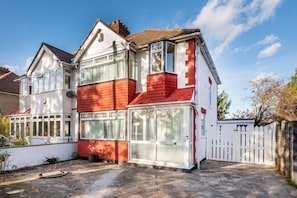 A two-story house with a red brick facade, large windows, and a white picket fence. - Modern Apartment in Enfield With Comfort (Enfield)