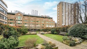 A courtyard with a brick building, a pathway, and a bench. - Charming 2-bedroom Apartment in London (London)
