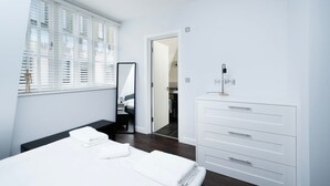 Ein modernes Schlafzimmer mit einem großen Bett, einem Schminktisch, einem Spiegel und einer Tür zu einem Badezimmer.