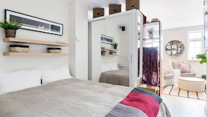 Een moderne slaapkamer met een groot bed, een kledingkast en een zithoek met een stoel en een klein tafeltje.