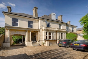 A two-story building with a symmetrical facade, a central entrance with steps, and a satellite dish on the roof. - Cozy One-bedroom Flat in Slough (Slough)