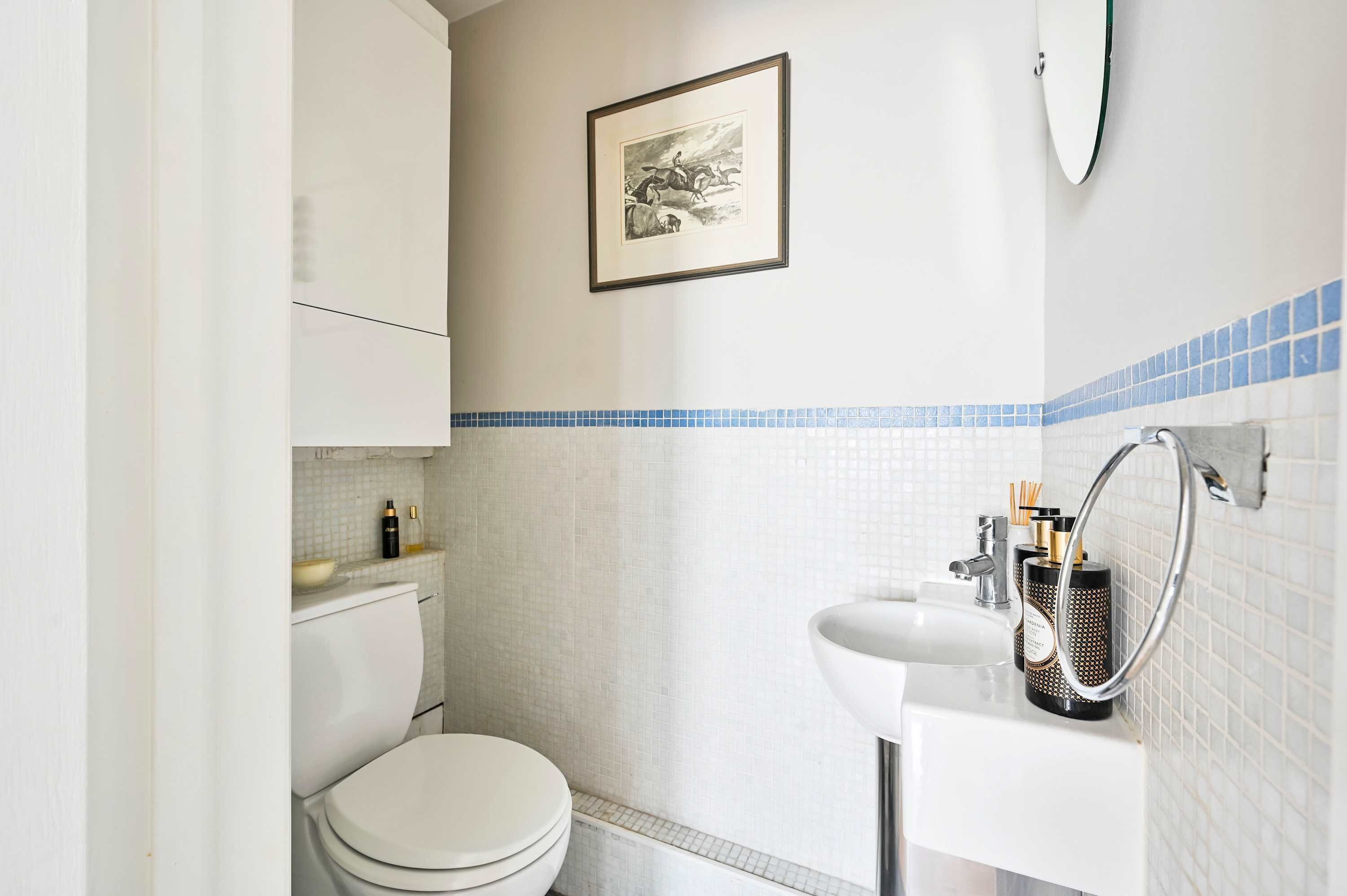A small bathroom with a toilet, sink, and a framed picture on the wall.
