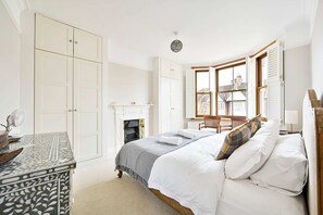 A bedroom with a bed, a dresser, a fireplace, and a window with shutters. - Chic House With Free Parking and Private Backyard (Harrow)